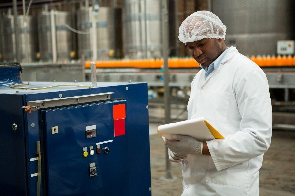 Serious male worker inspecting machines at juice factory